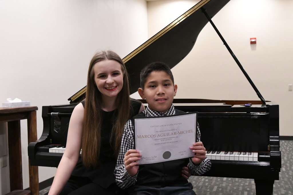 Anastasiia Soliar with a piano student beside a grand piano