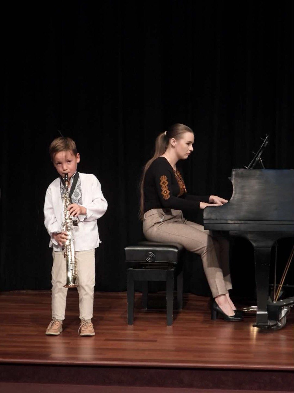 Anastasiia accompanying a young musician during a stage performance