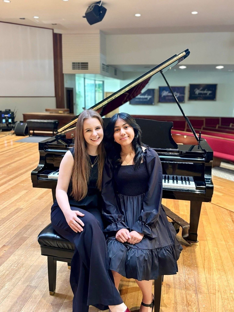 Anastasiia with a student beside a grand piano after a performance