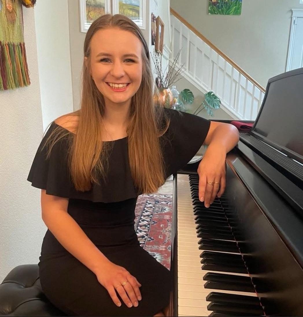 Piano teacher Anastasiia Soliar seated beside her piano